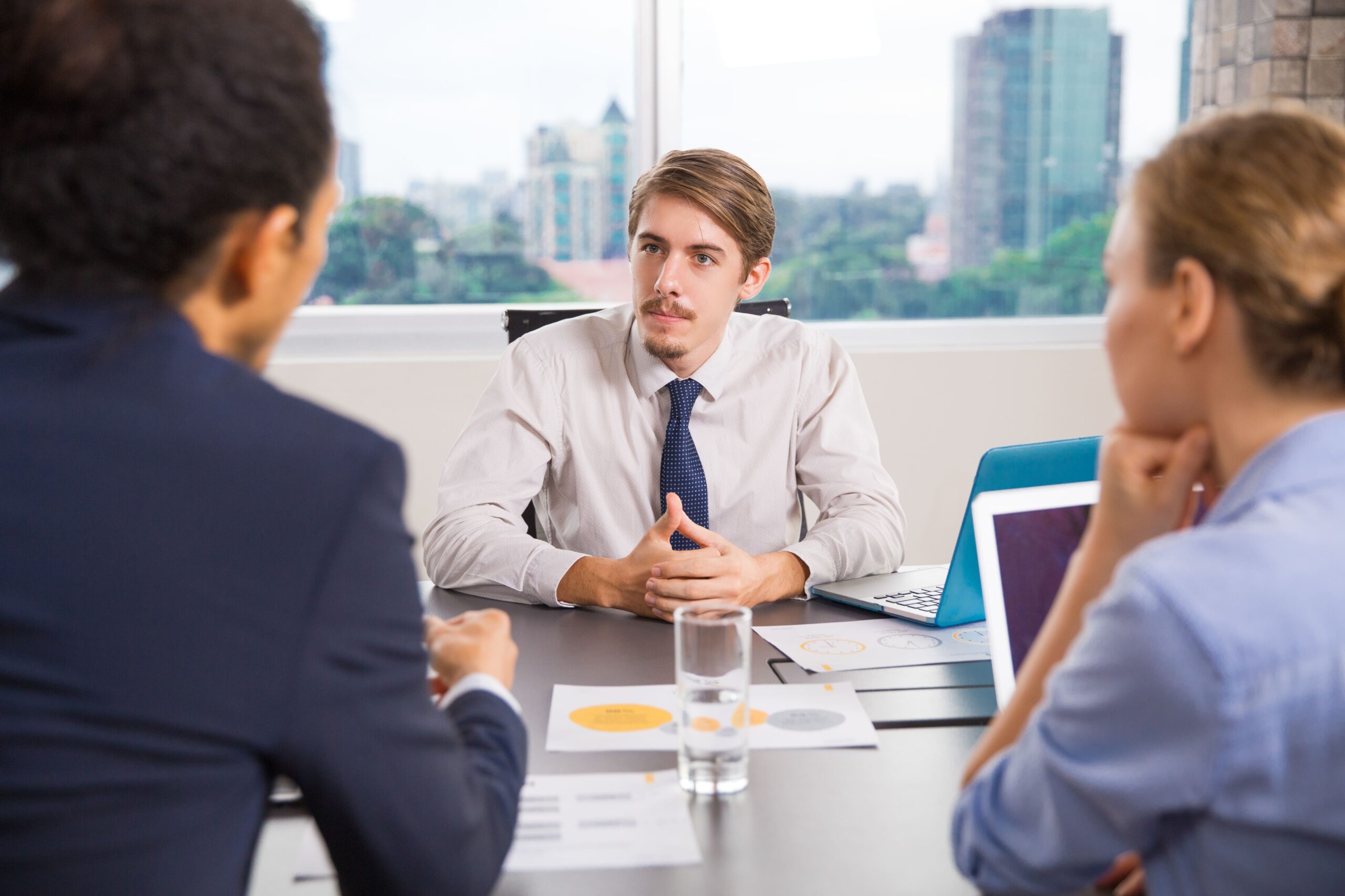 businessman-sitting-with-laptop-talking-other-colleagues